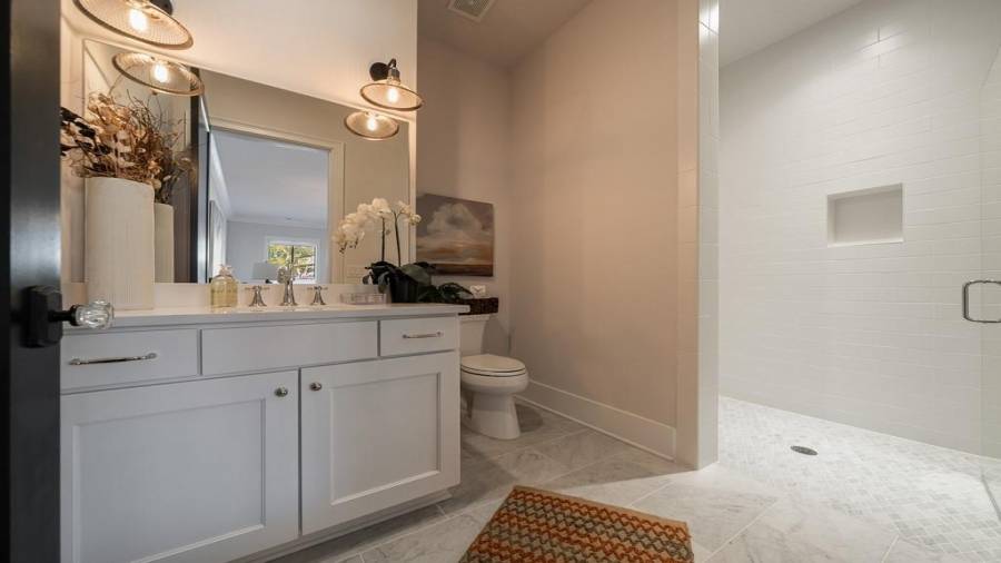 Seamless entry into the spacious shower with diamond patter marble floor in shower and square pattern on the main floor in front of vanity and toilet.