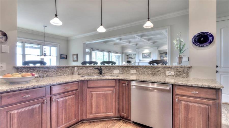 Kitchen sink and the dishwasher located in the island lends plenty of space for food preparation. Beautiful granite countertops and pendant lighting above the island.