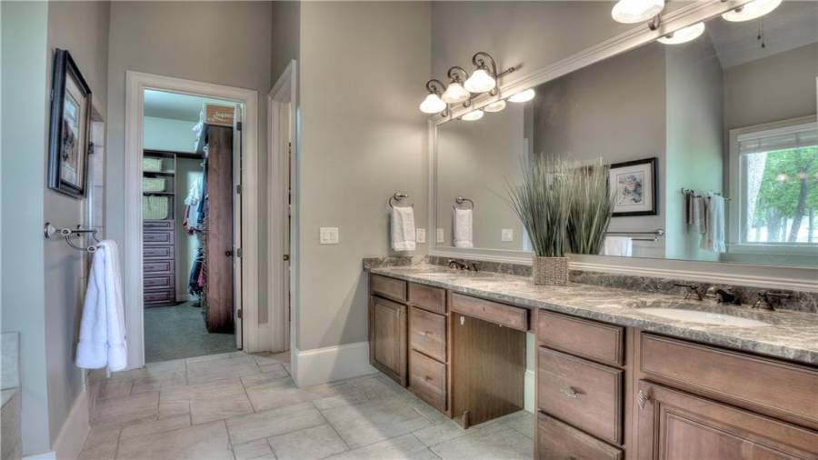 Master bath with granite countertops, wood cabinets and tile floor and shower with a walk-in closet.
