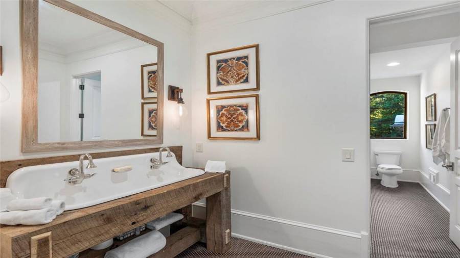 Spacious bunk room bathroom with double sink and wooden vanity.