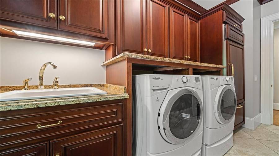 Another view of laundry room, showing sink and a built in wood panel refrigerator.