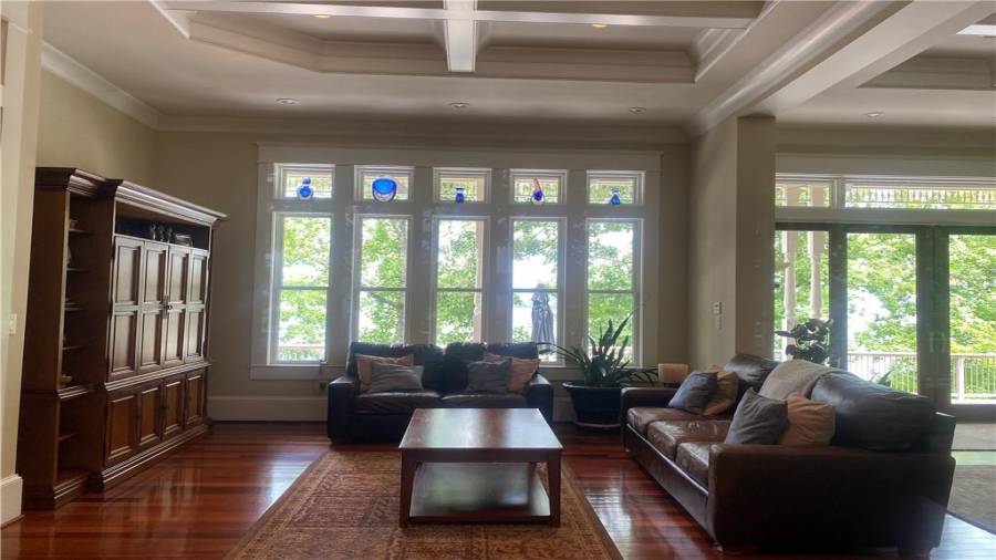The family room is open concept living. View of the dining room, kitchen, foyer, and the wall of windows and doors overlooking the lake.  So much natural light makes this a excellent area to hang out or entertain.