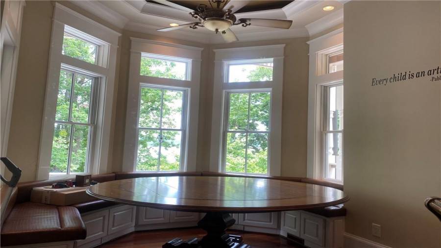 Breakfast area offers amazing lake views, built in seating, storage under the seating area, custom table, trey ceiling, view of kitchen, dining room, and living area. Custom wood working and trim through out the house.