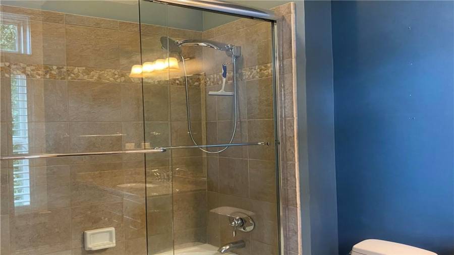 This full bath offers tiled sides on the tub. Views of the lake and front yard from the shower. Tiled floor and plenty of storage in the vanity cabinet.