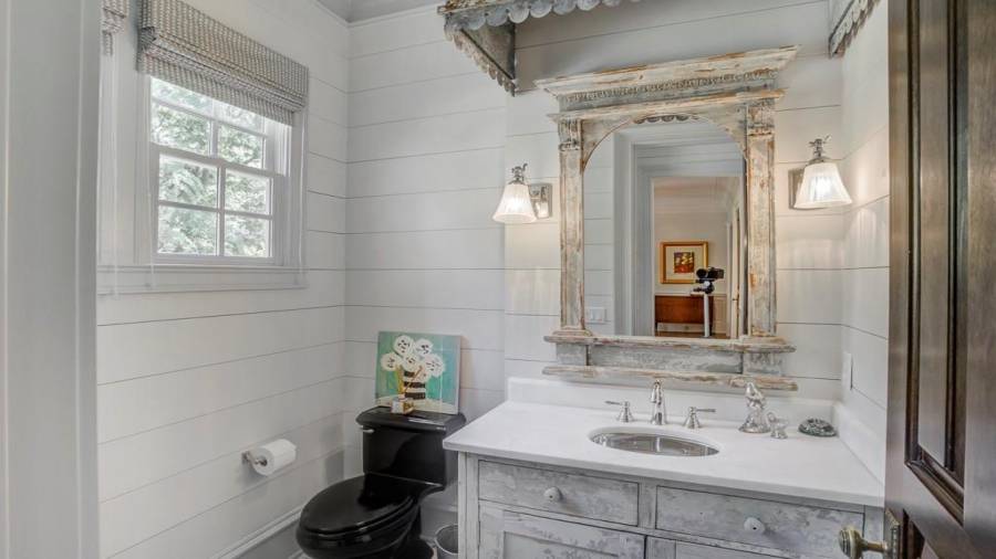Main level powder room has custom rustic French cabinet, nickel sconces, and shiplap walls.