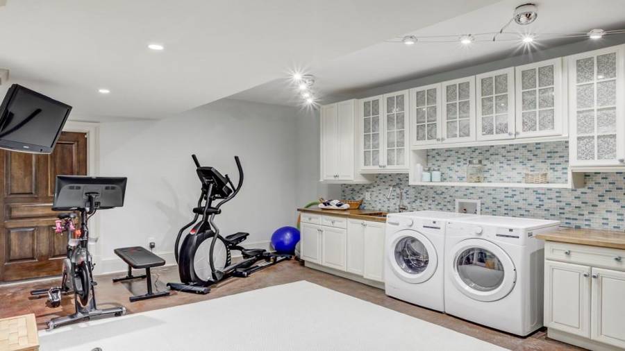 Laundry room large enough for machines, prep areas, and work out equipment. Mirrored wall to the left.