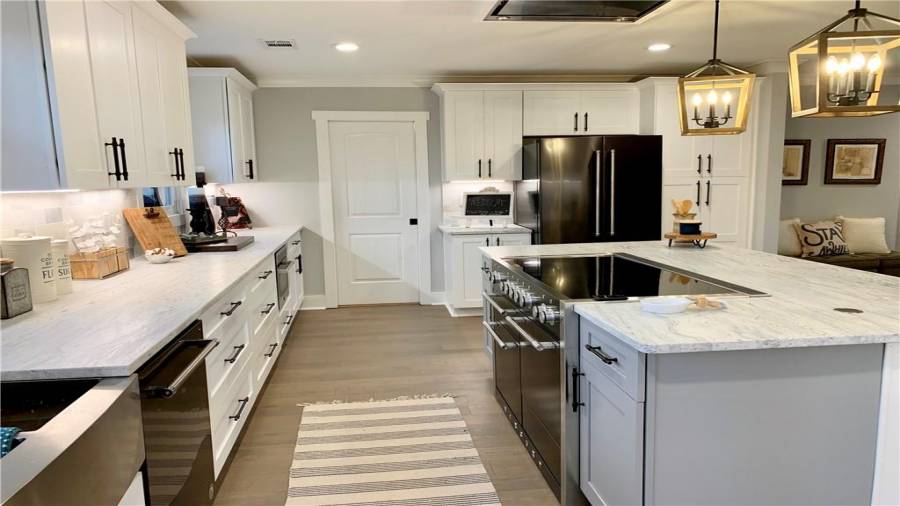 Gorgeous leathered granite counters with white shaker wall cabinet and gray shaker island cabinets
