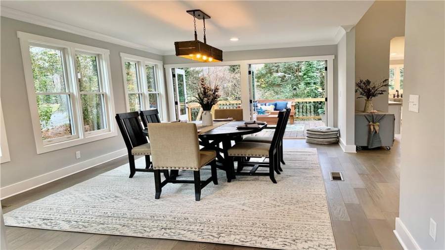 Double French doors in dining room lead to deck and have magnetic door catches to hold doors open
