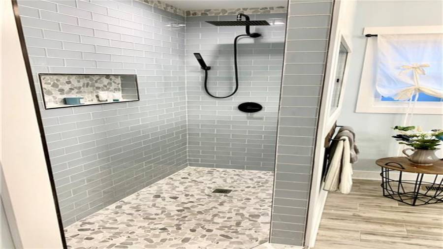 Glass tile with pebble rock accents. 12” rainshower head with handheld sprayer and oversized niche!