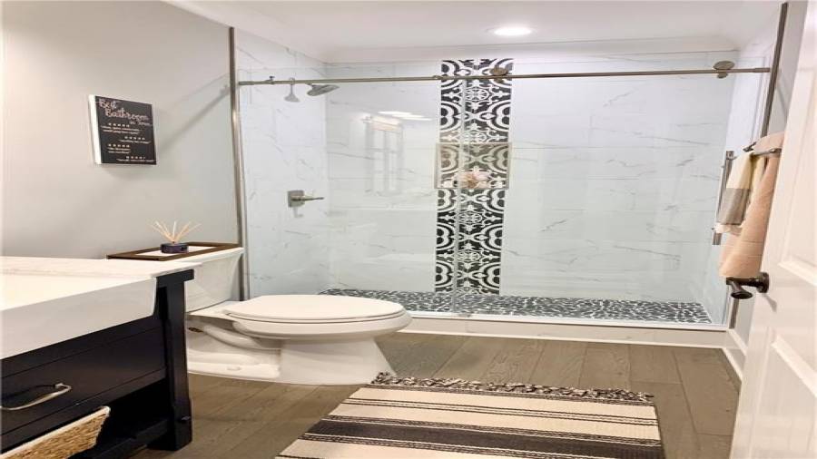Guest bath on main level offers gorgeous shower with frameless sliding doors & farmhouse sink vanity in navy blue!