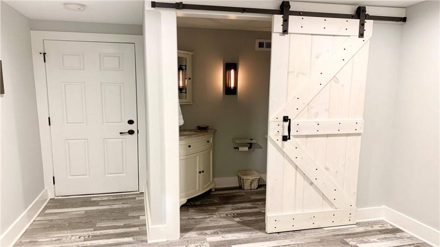 Adorable half bath has corner vanity & mirror with barn door that latches inside