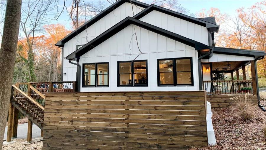 Walls of windows in dining room overlook river rock patio area with privacy fence