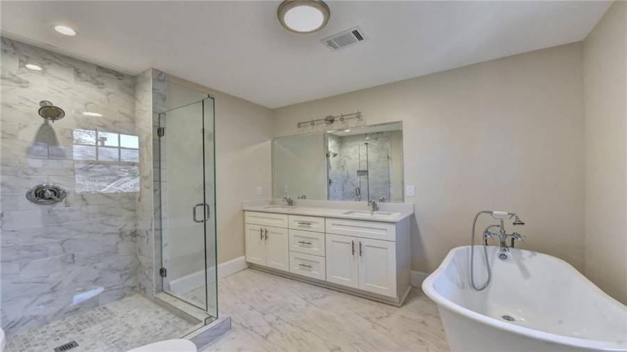 Master bathroom on main with designer tiled floors, separate glass shower, cast iron clawfoot tub, dual vanities with Quartz