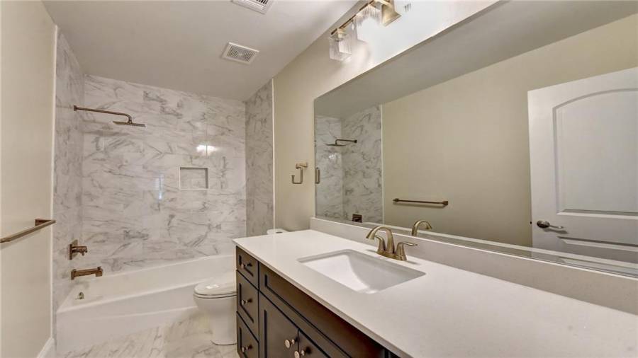 Guest bathroom on main level features new quartz vanity, designer tile and lighting