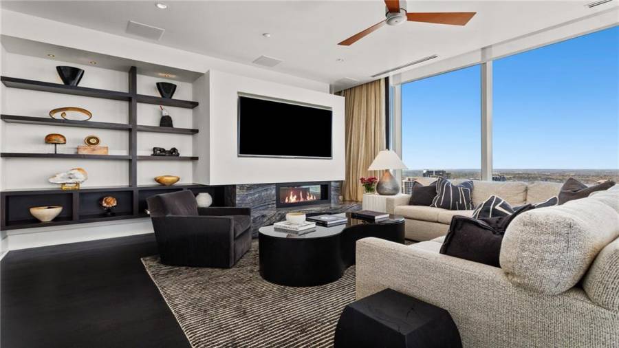 The Sunset and Buckhead Skyline Facing Den is 17 x 29 and Offers Stunning Views Of Buckhead and Midtown. Note Two Seating Areas and The Natural Gas Fireplace And Built-In Television Panel and Custom Built-Ins To The Left Of The Television. The Kitchen Opens to This Space for A Casual Family Lifestyle And Effortless Entertaining.